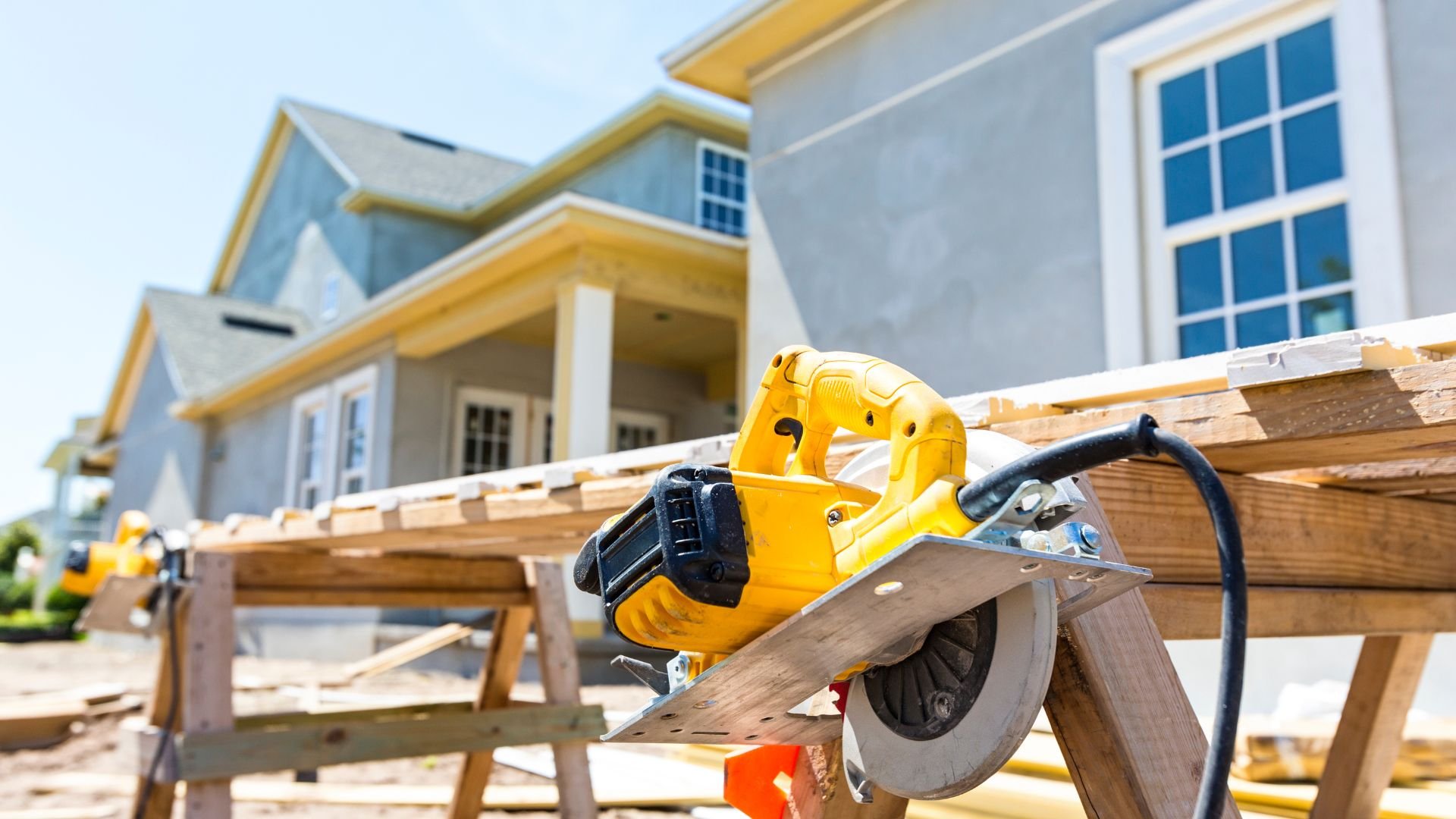 Yellow circular saw on wooden boards at residential construction site