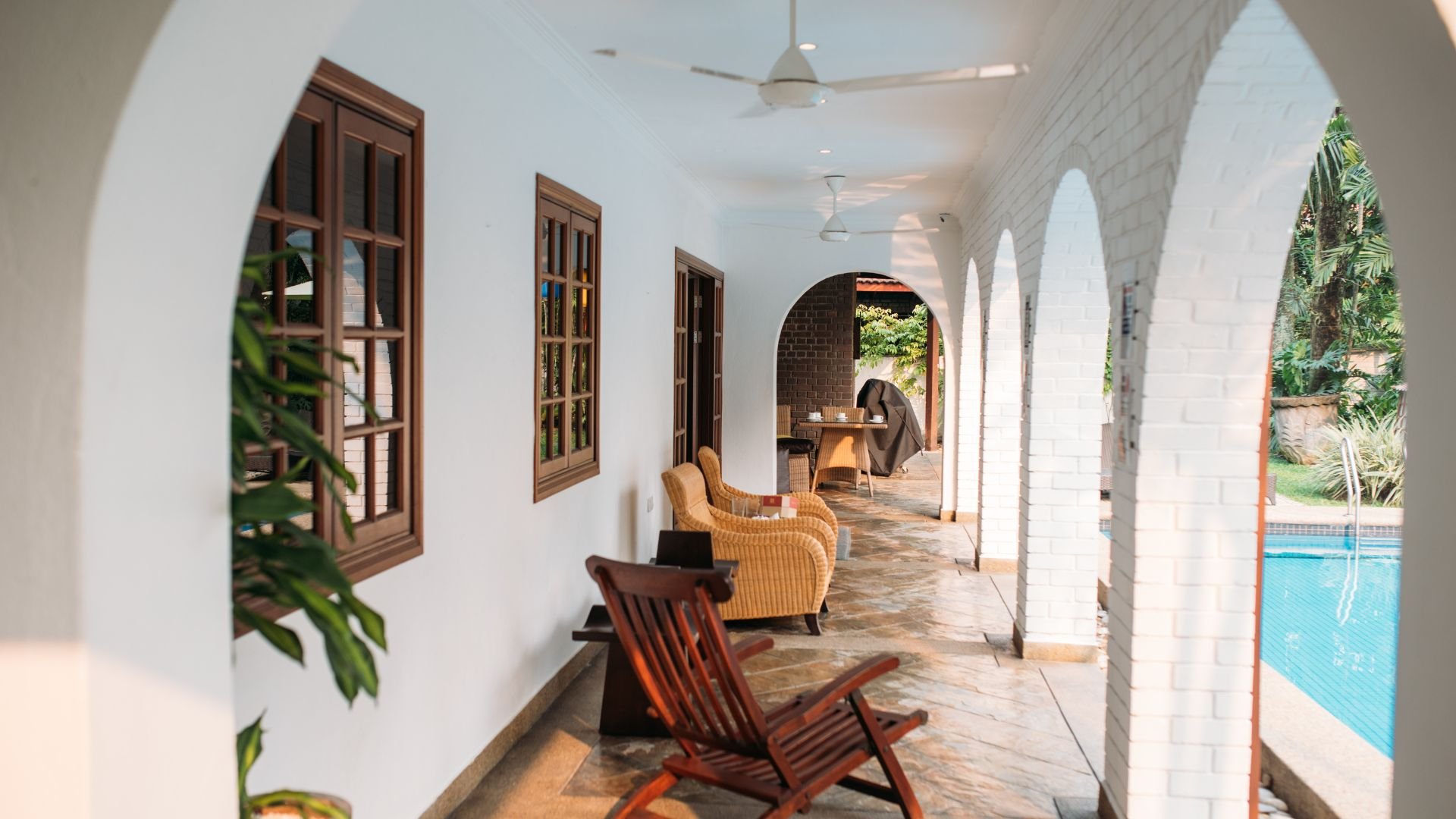 Sunny arched patio with wicker chairs, pool view, and white walls