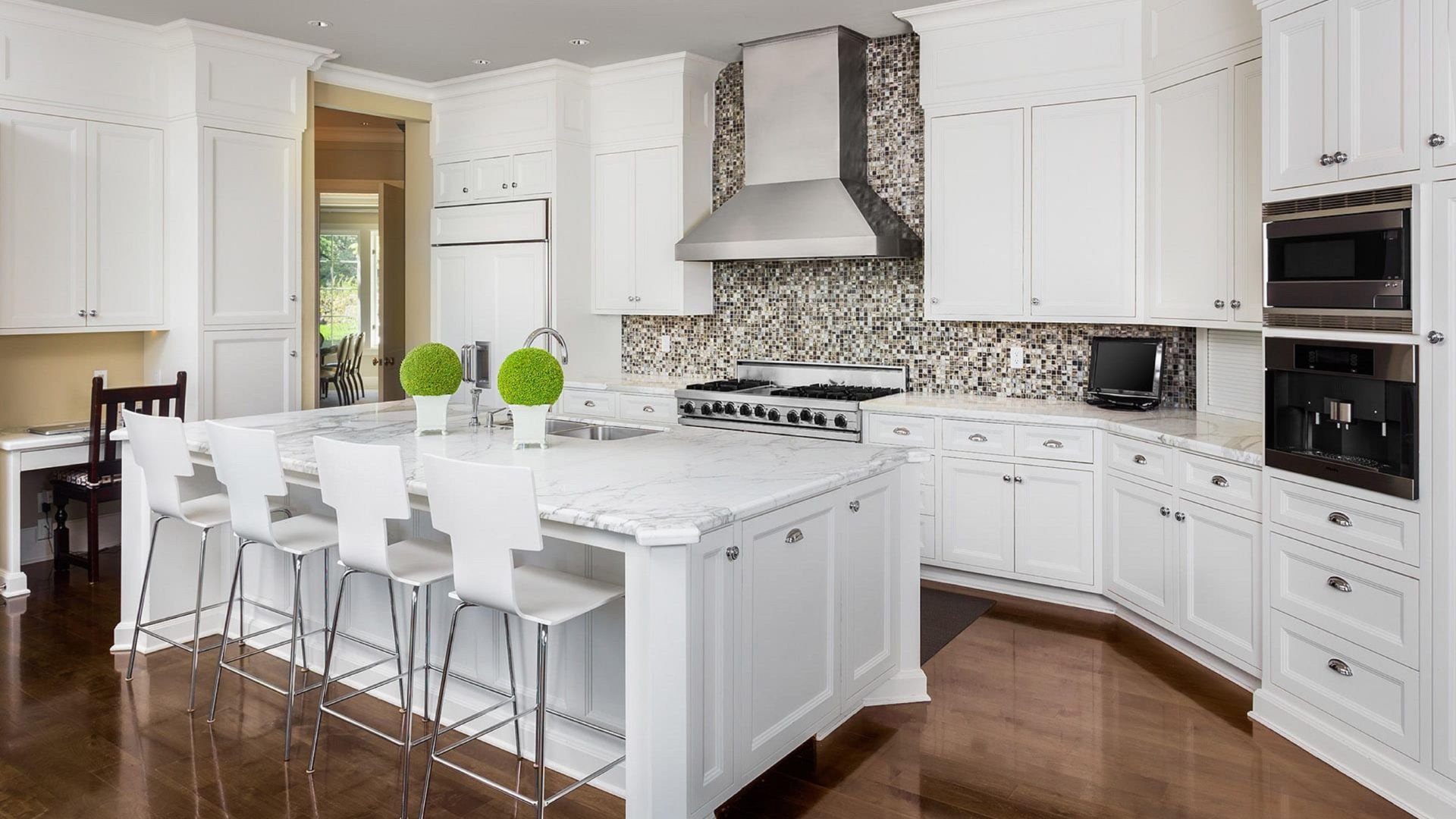 Modern white kitchen with marble island, mosaic backsplash, and bar stools