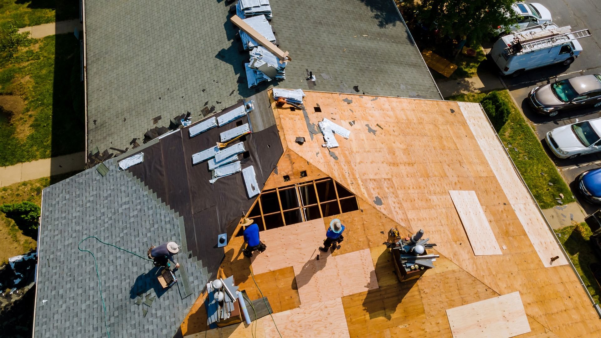 Aerial view of construction workers installing roof shingles on house