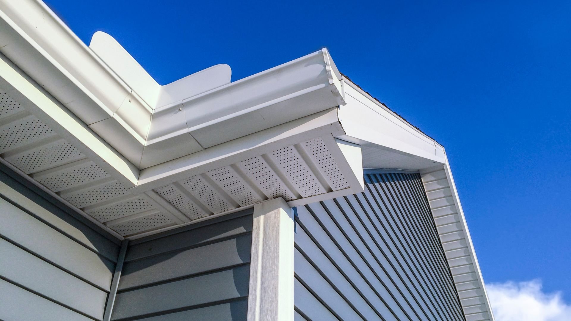White modern building exterior with geometric roof against bright blue sky
