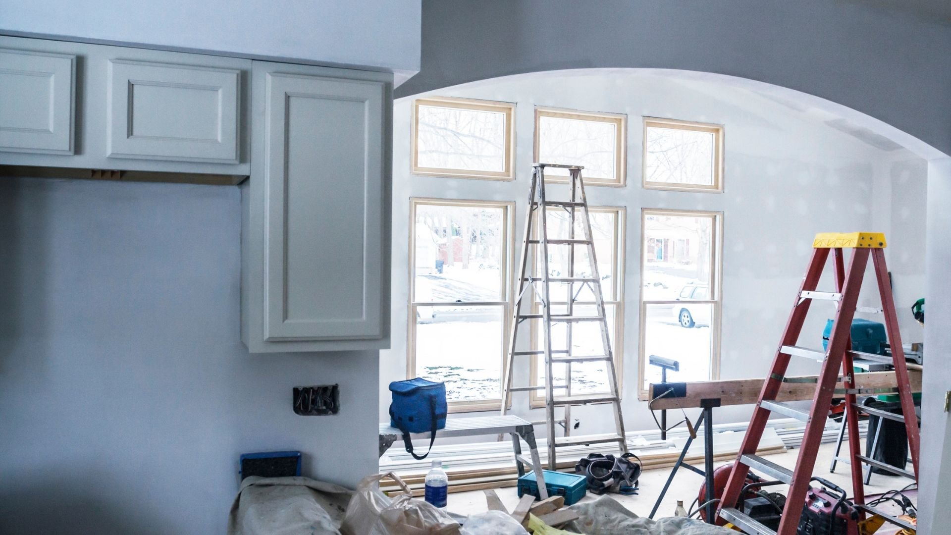 Home renovation in progress with ladders, tools, and unfinished interior